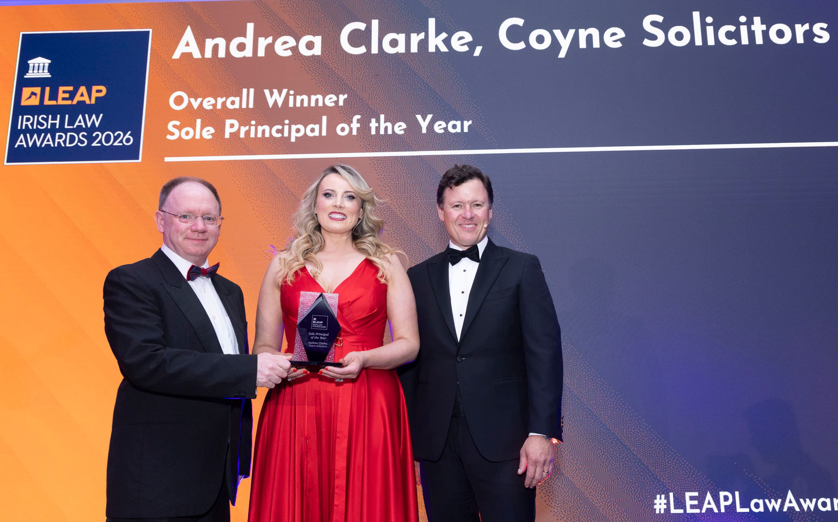 Andrea Clarke of Coyne Solicitors accepting the Sole Principal of the Year award in a red dress on stage at the LEAP Irish Law Awards 2026
